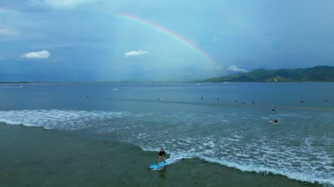 Surfers riding ocean wave under vibrant rainbow. Magic aerial view drone Stock Footage 344619648