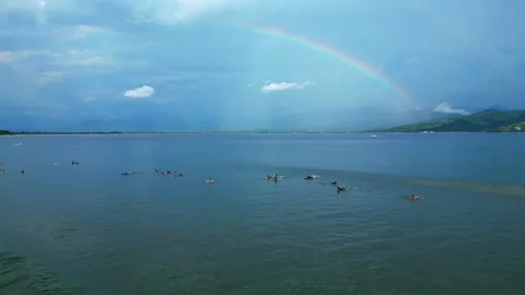 Surfers riding ocean wave under vibrant rainbow. Smooth aerial view drone 스톡 동영상 344623819