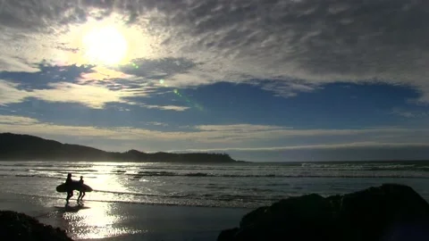 Surfers runing on a beach with partly cloudy sky Stock Footage 202109581