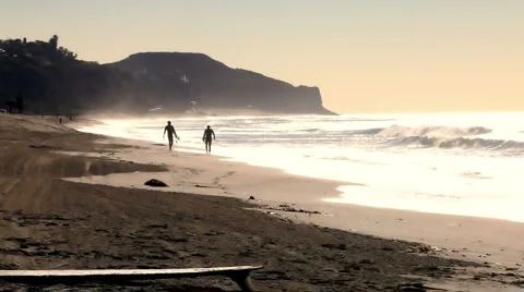 Surfers on shore 03 - walking down beach at sunset Stock Footage 5296541