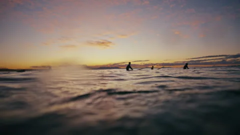 Surfers Sitting Beyond Small Waves at Sunrise Stock Footage 331970255