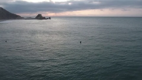 Surfers sitting in ocean at sunset Vidéo 75693837
