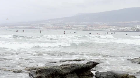 Surfers skillfully Riding Waves on a Gloomy Day by the Shoreline Stock Footage 315771282