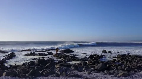 Surfers standing on rock with wave Stock Footage