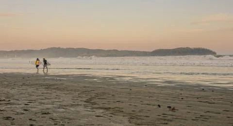 Surfers at sunset on the beach Stock Photos