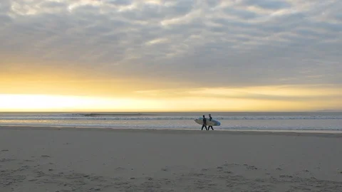 Surfers walking on the beach at sunset time / golden hour 4k 30fps Stock Footage