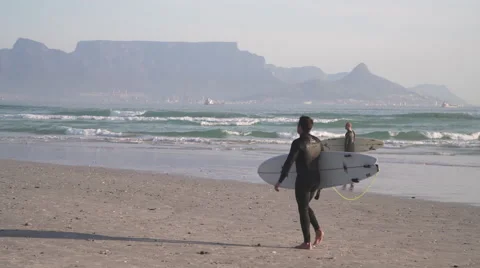 Surfers walking on Beach with Table Mountain in Distance, Cape Town 스톡 동영상 60110343