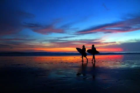 Surfers walking at sunset Stock Photos