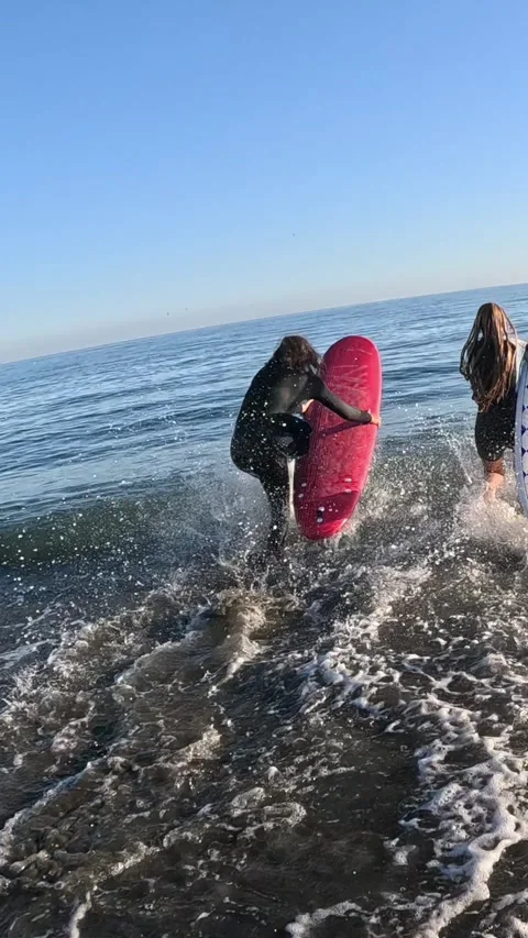 Surfers wearing wetsuits walking on a sandy beach and entering the ocean Vídeos de archivo 347280353