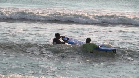 The surfing instructor teaches to ride on the board in the ocean. Stock Footage 112321622