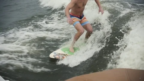 Surfing a Wave, Man on surfboard or wakeboard in ocean with boat, cable Stock Footage