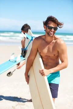 Surfs up. Two friends at the beach getting ready to head into the water for a Stock Photos