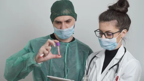 Surgeon And Doctor with facemasks Looking At Patient Blood sample and tests Stock Footage 126575365