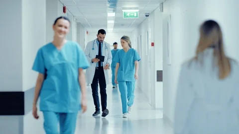 Surgeon and Female Doctor Walk Through Hospital Hallway Stock Footage
