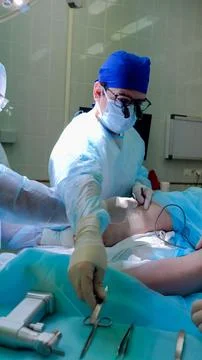 Surgeon and operating team performing sterile abdominal procedure on draped Stock Photos