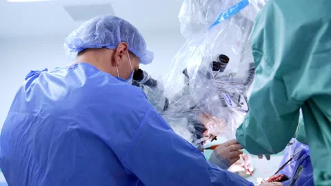 Surgeon in blue uniform leaned over the microscope at operation.  Stock Footage 307941119