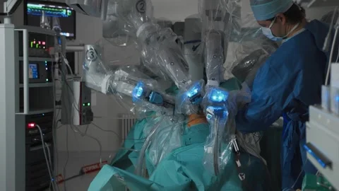 Surgeon controls robot with multiple arms and performs surgical procedure Stock Footage 246621901