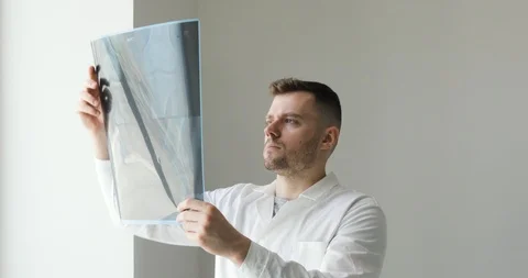 Surgeon diagnostics damage of bones on x-ray images standing near the window. Stock Footage 108021247