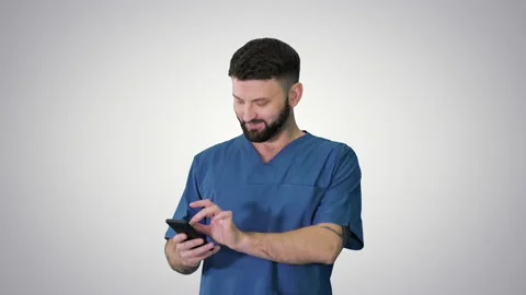 Surgeon doctor walking and using his phone on gradient background. 스톡 동영상 140529456