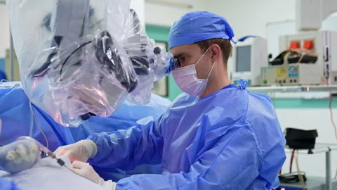 Surgeon looks attentively into the microscope binoculars. Stock Footage 306693307