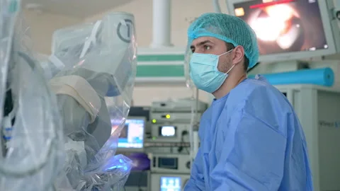 Surgeon looks focused at the screen controlling the work of Da Vinci robot.  Stock Footage 212425713