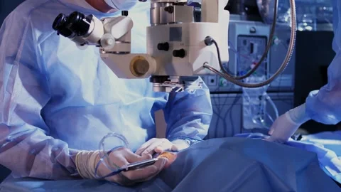 A surgeon looks through a microscope at a patient's eyes in the operating room Stockbeeldmateriaal 265012570