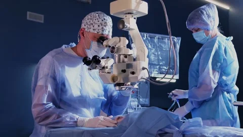 A surgeon looks through a microscope at a patient's eyes in the operating room Stockbeeldmateriaal 265013764