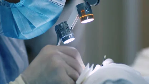 Surgeon operates using microscope glasses with lenses and lamps. Microsurgery Stock Footage 178491063