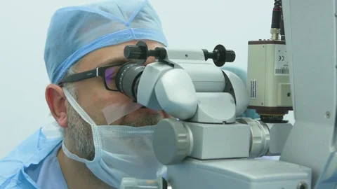 Surgeon operating on a patient's eye and his staff assisting him Stock Footage 77447049