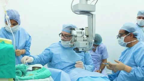 Surgeon operating on a patient's eye and his staff assisting him Stock Footage 77447119