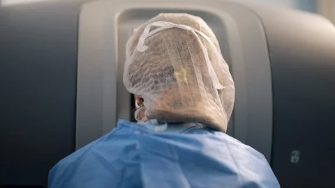 Surgeon operating at the robotic console in operations room using robotic arm 動画素材 102187246