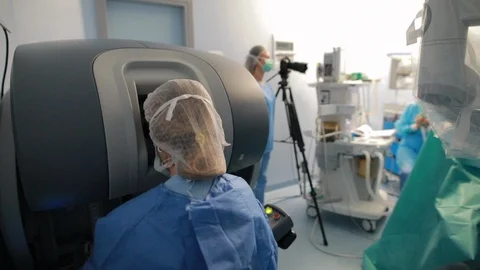 Surgeon in operationg room using davinci console with robotic surgery robot i Stock Footage