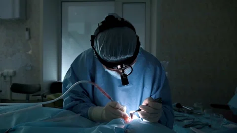 Surgeon performing delicate operation under bright surgical light Stock Footage 306167558