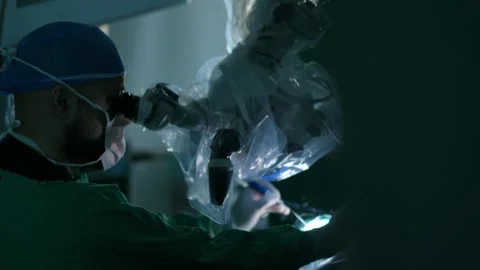 Surgeon performing delicate procedure using operating microscope during reveal Stock Footage 308913551