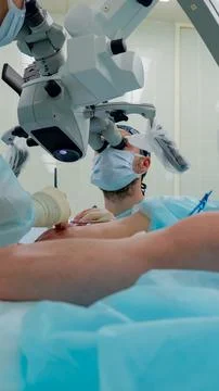 Surgeon performing microsurgical procedure using operating microscope over Fotos de archivo