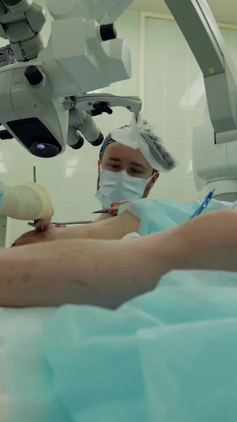 Surgeon performing progressive microsurgery under ceiling mounted microscope Stock Footage 339347145