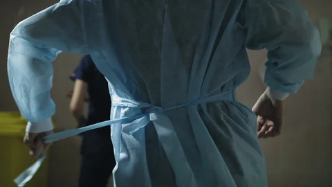 Surgeon removes and throws out the medical dressing gown after the operation Stock Footage