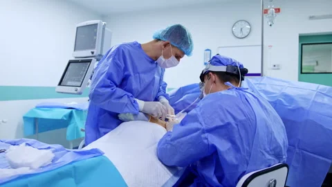 Surgeon sitting his back to camera performs surgery on arm. Stock Footage 281304251