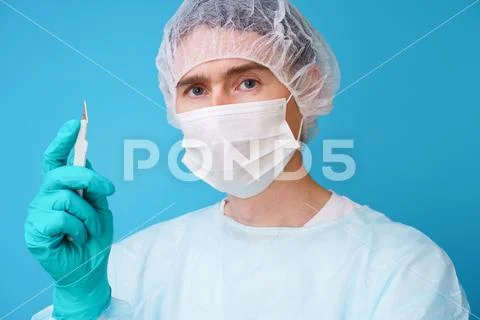 Surgeon in sterile blue uniform, medical gloves and mask Stock Photos