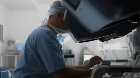 Surgeon uses controllers to remotely operate patient with medical robot Stock Footage 241822097