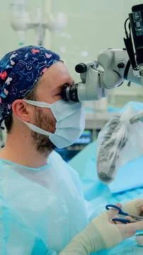 Surgeon using operating microscope during microsurgery wearing surgical cap Fotos de archivo