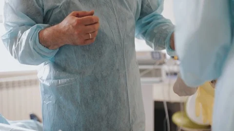 The surgeon wears gloves with the help of an assistant Stock Footage 116814553