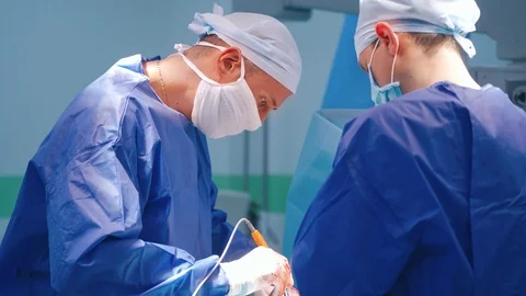 Surgeons during the operation. Specialists men in blue medical uniform Stock Footage 125894905