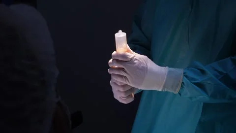Surgeon's hands in sterile gloves preparing a large syringe with harvested fat Stock Footage 345682202