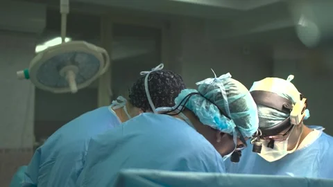 Surgeons leaning over operating table during surgery Video stock 288805605