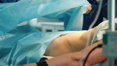 Surgeons in the operating room prepare the patient for surgery. They discuss the Stock Footage 219424632