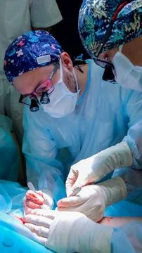 Surgeons performing delicate open operation under bright operating lights with 库存照片