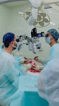 Surgeons performing precise open medical procedure under operating microscope Fotos Stock