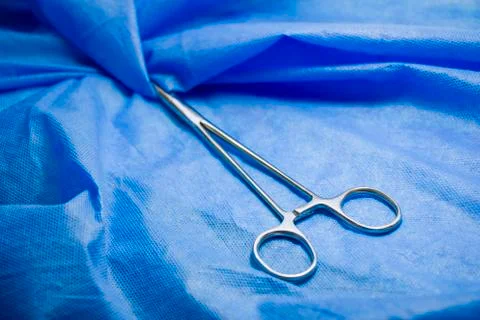 Surgery forceps on the blue background, studio shot. Operation equipment. Sur Stock Photos