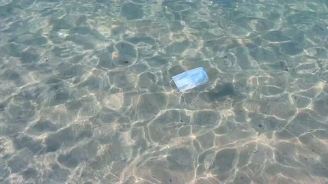 Surgical blue protective mask floating in the water Stock Footage 146879680